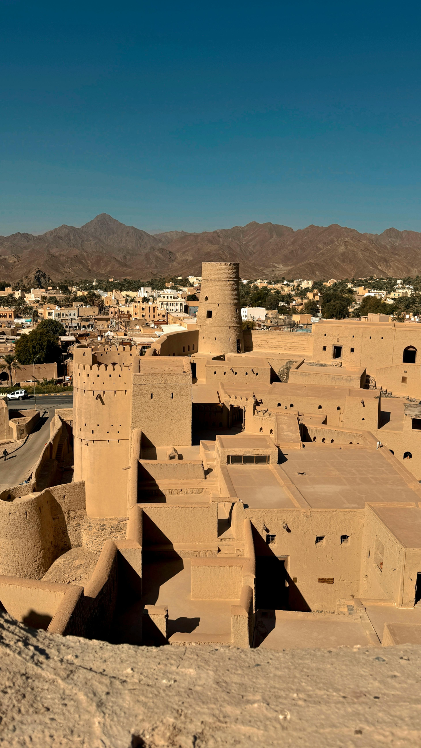 A stunning view of Bahla Fort in Oman, showcasing its desert architecture and mountainous backdrop.